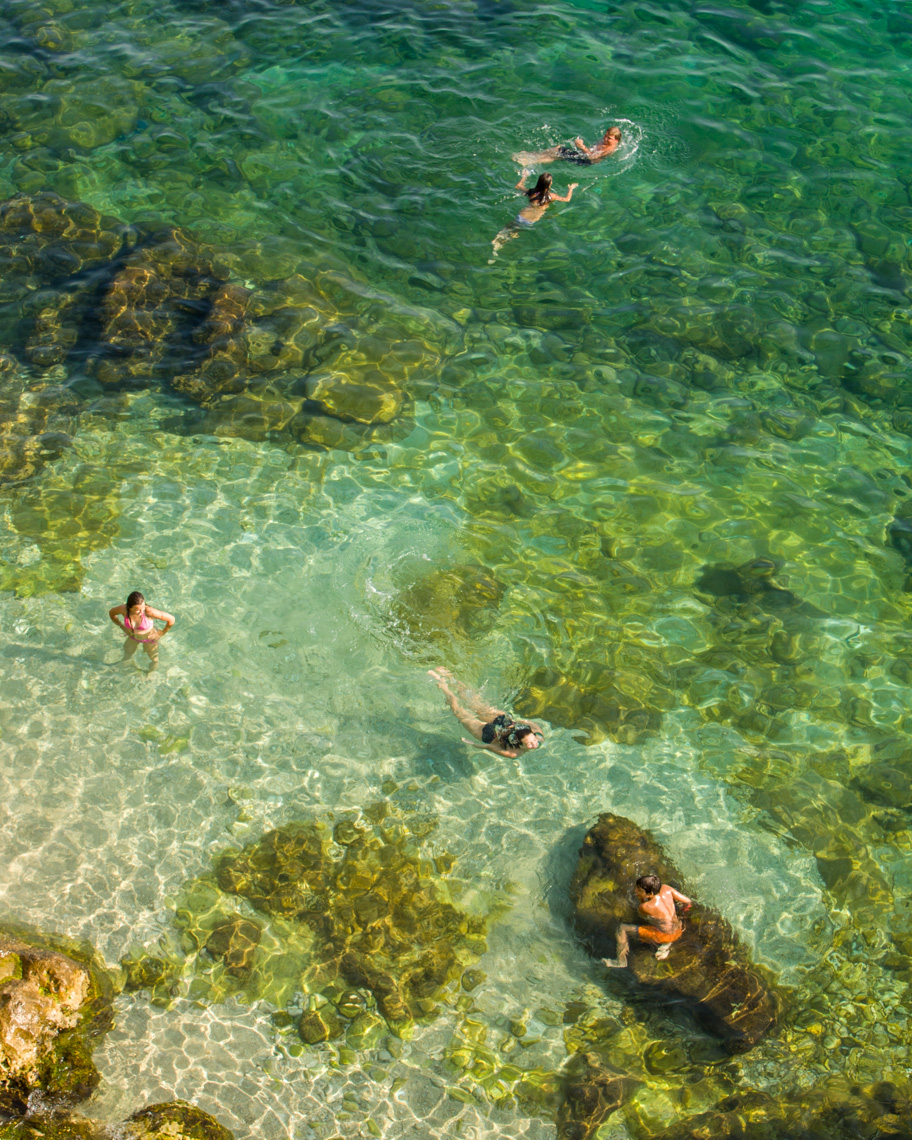 People swimming in clear rocky waters in sea