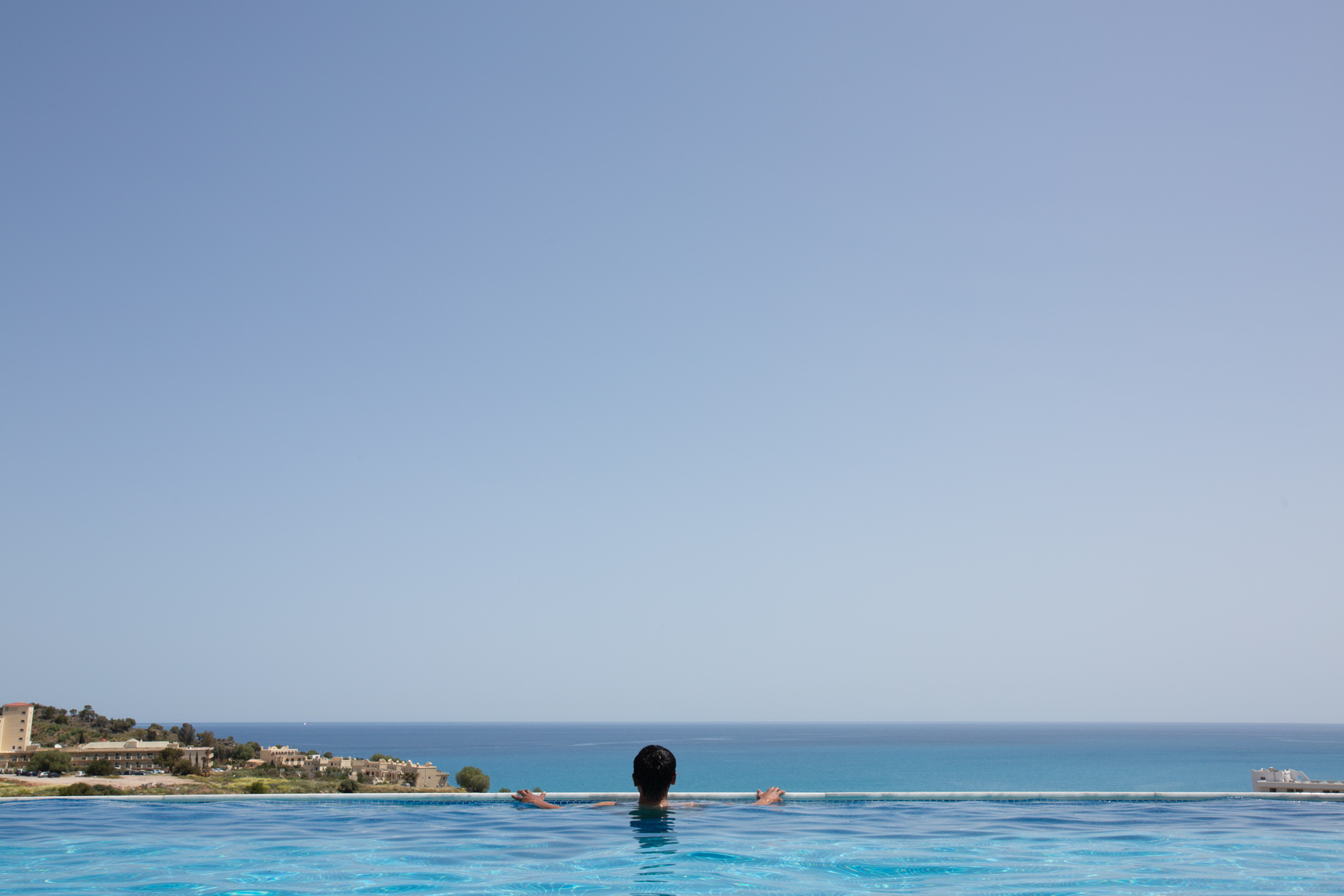 Person in swimming pool overlooking ocean
