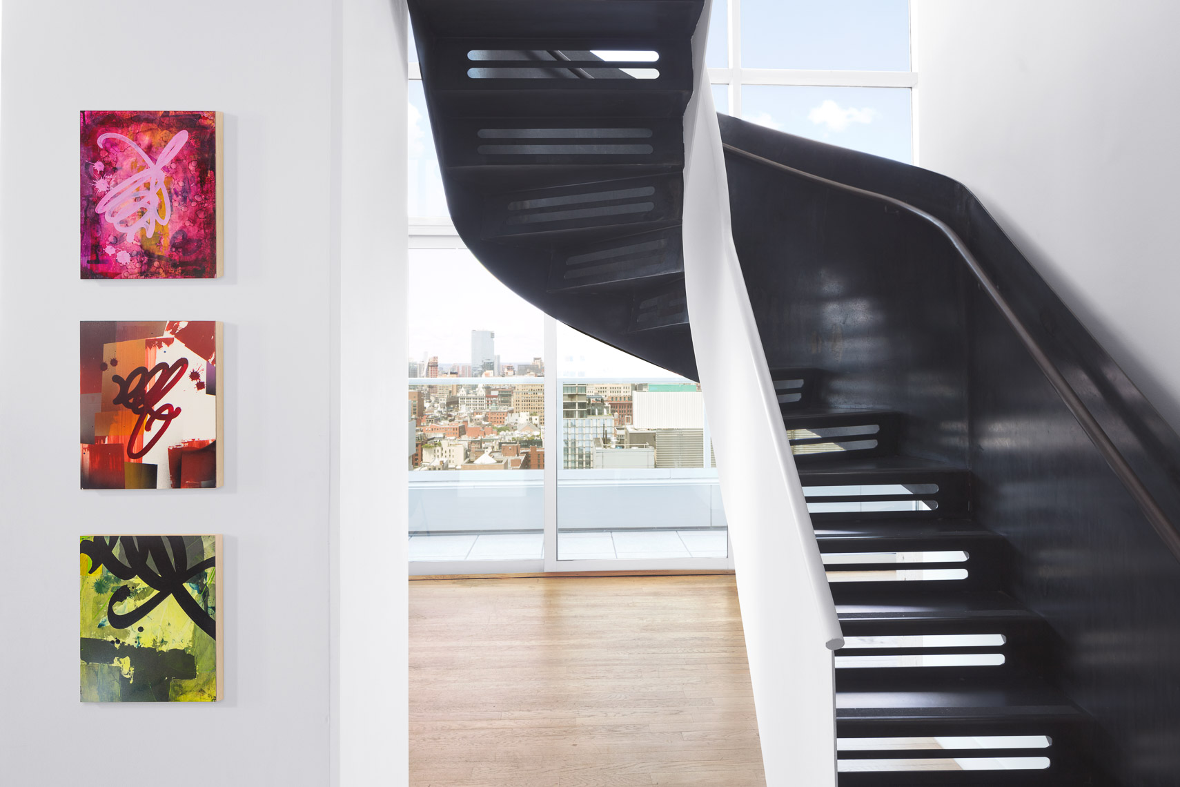 Curved metal staircase and graffiti artwork in hotel room with panoramic city views
