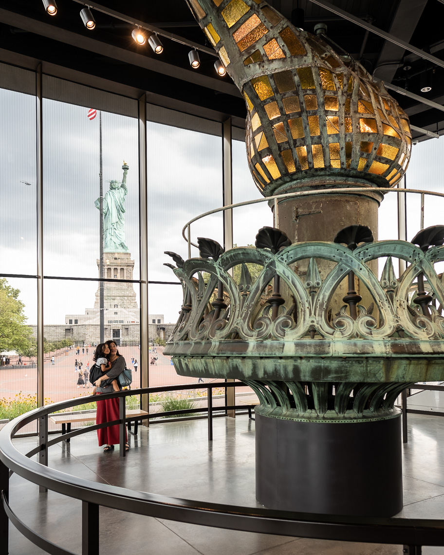 Mother and child inside museum looking at Statue of Liberty torch