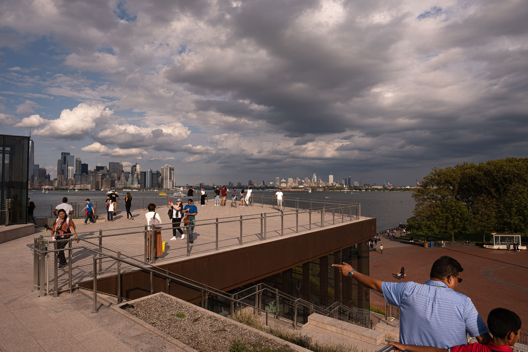 People gather on the roof of a building with views of New York harbor and Manhattan skyline 