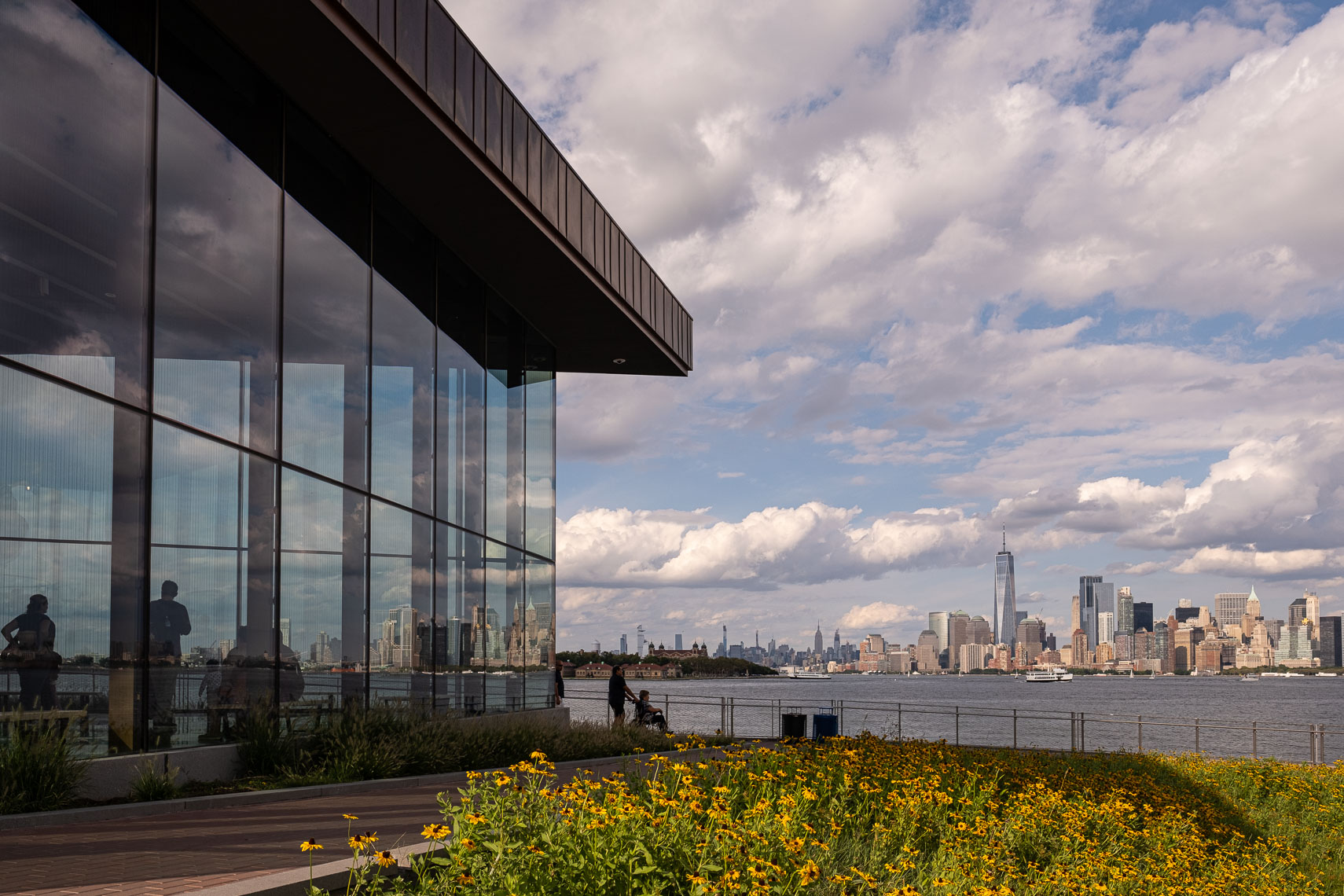 Exterior view of glass walled museum building with Manhattan skyline in the distance