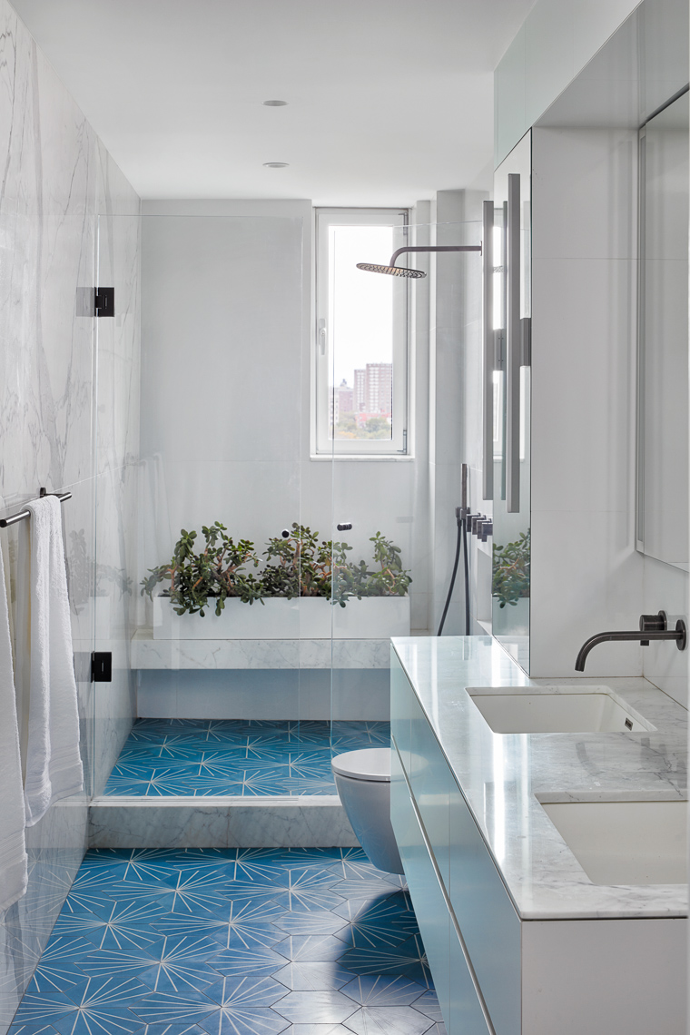 Straight view of white marble and blue tiled bathroom