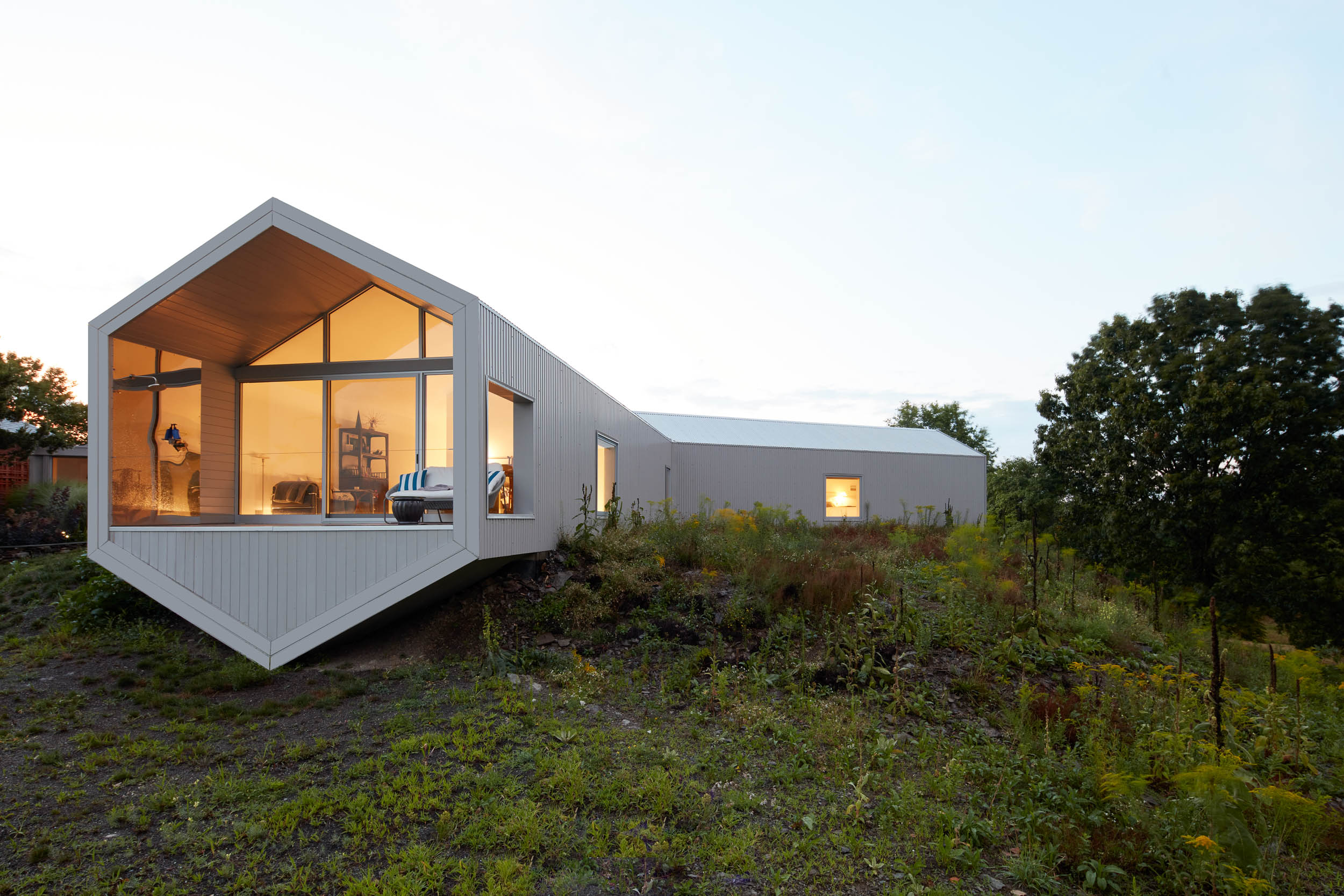 Warmly lit hexagonal modern home designed by artist Ai Weiwei set in a lush green rural area