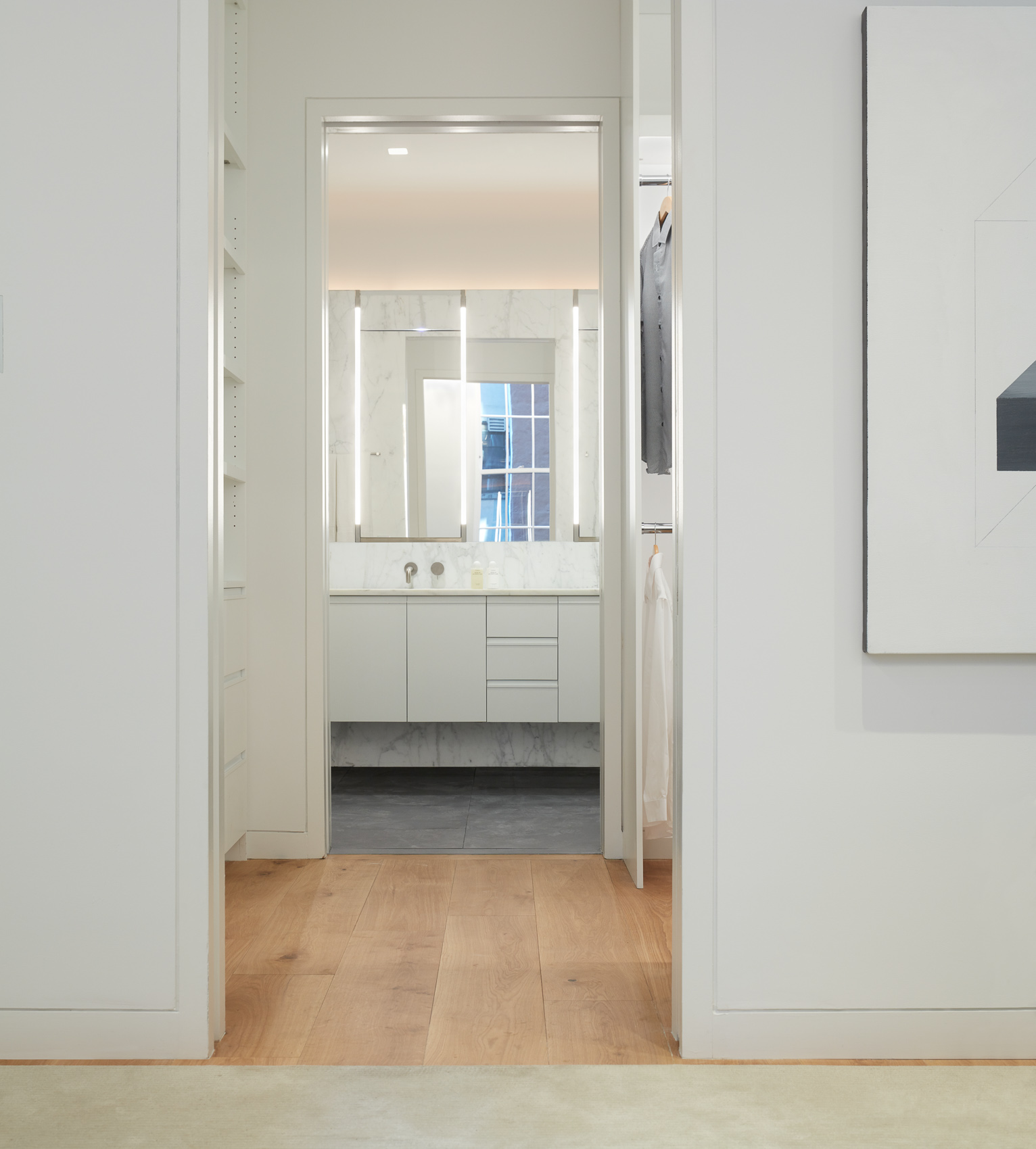 Doorways leading through the closet to a bathroom in a modern luxury apartment