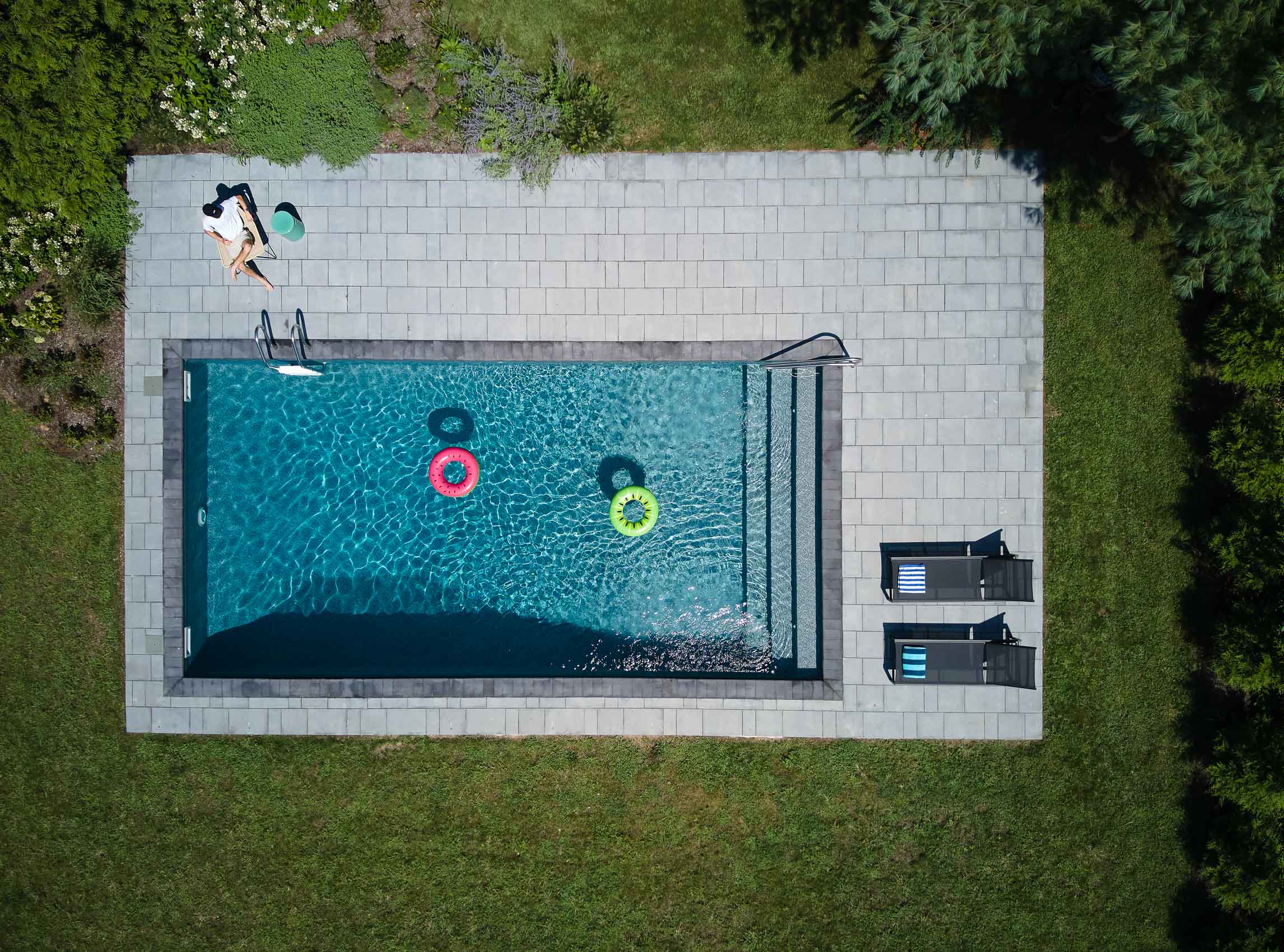 Overhead shot of blue swimming pool with person sitting 